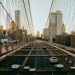 View of Brooklyn Bridge with Manhattan skyline at sunset, capturing urban life and architecture.