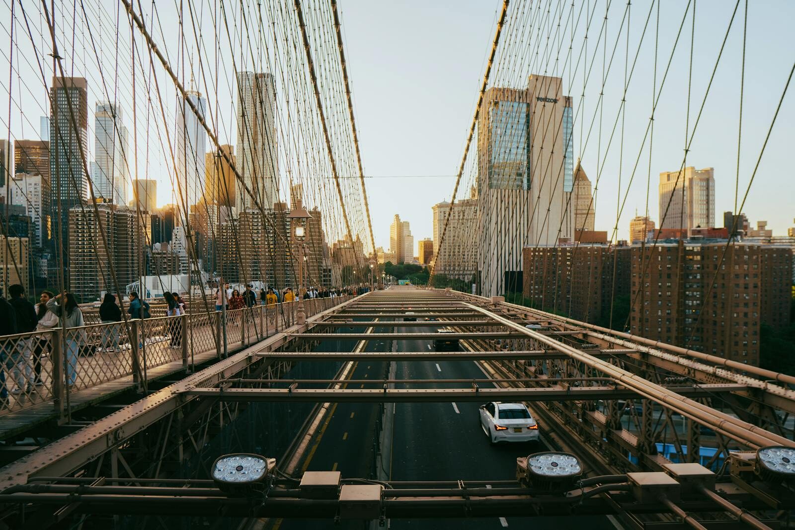 View of Brooklyn Bridge with Manhattan skyline at sunset, capturing urban life and architecture.
